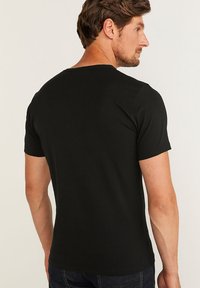 Zwarte korte mouwen t-shirt met een ronde halslijn, voorzien van een gladde textuur en een slim fit design, zichtbare stiksels op de schouders.