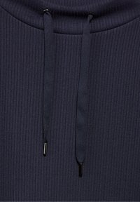 Granatowy, rypsowy top z kapturem, z regulowanymi sznurkami i czarnymi metalowymi końcówkami. Miękka tekstura i dopasowany krój, podkreślający pionowe linie.