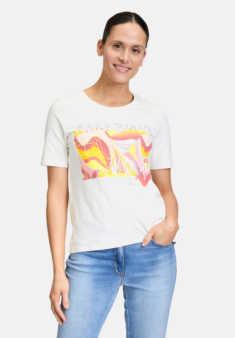 White short-sleeve t-shirt featuring a colorful abstract design in pink and yellow with glittery text "AMAZING" above the graphic.