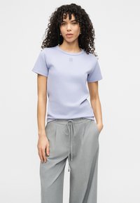 Μωβ κοντομάνικη μπλούζα με στρογγυλή λαιμόκοψη και κεντημένο λογότυπο "HUGO", συνδυασμένη με ανοιχτό γκρι παντελόνι με κορδόνι. Λείο ύφασμα.