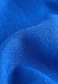 Tissu bleu lisse et vibrant avec une texture de tissage fin et de doux plis créant des ombres délicates et de la profondeur.
