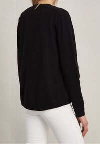 Pull en maille noir à manches longues, avec un col rond et une coupe décontractée. Texture lisse et coutures discrètes le long des épaules et de l'ourlet.