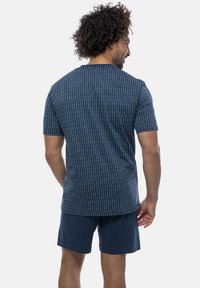 Kortærmet navystribet skjorte med lyse lodrette linjer, rund hals og afslappet pasform, båret med navy shorts. Glat tekstur.