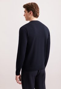 Maglione a maglia blu navy con scollatura rotonda, polsini e orlo a costine. Texture liscia, design aderente, senza loghi o pattern visibili.