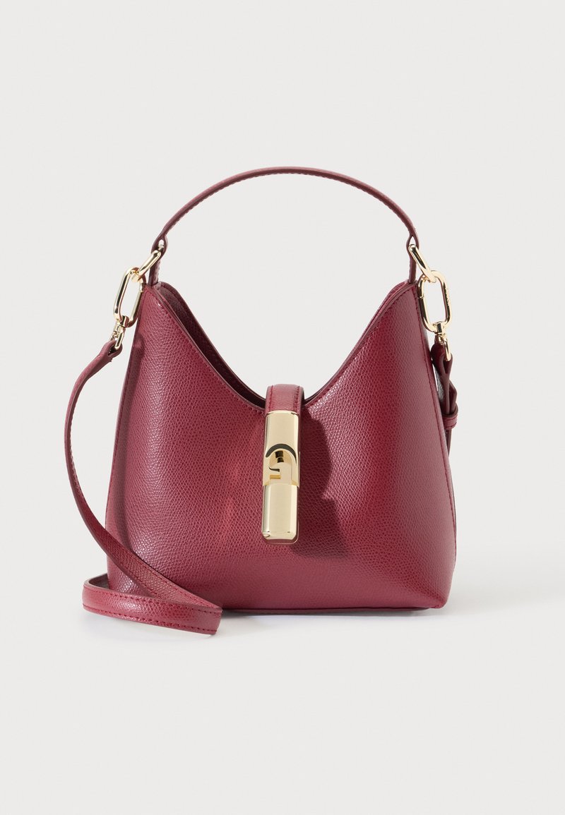 Petit sac à main bordeaux texturé avec poignée courte, bandoulière longue détachable et fermoir central doré sur fond uni.