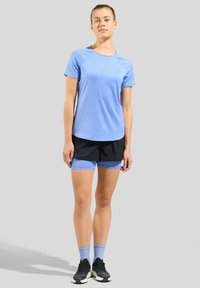 Light blue short-sleeve athletic shirt paired with black shorts featuring blue accents. Black athletic shoes and light blue socks complete the look.