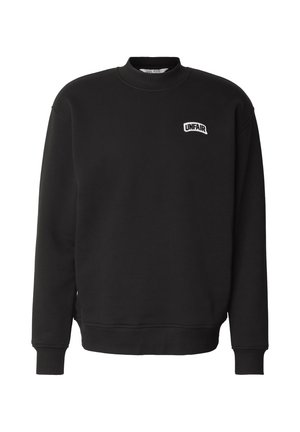 Felpa nera con collo tondo con polsini e orlo a coste, con una piccola toppa bianca con la scritta "UNFAIR" sul petto a sinistra.