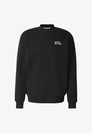 Felpa nera con collo tondo con polsini e orlo a coste, con una piccola toppa bianca con la scritta "UNFAIR" sul petto a sinistra.