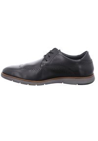 Zapato de vestir de piel negra con detalles texturizados, puntera redondeada, diseño de cordones y suela de goma gris con acento marrón.
