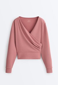Haut à manches longues en maille côtelée couleur rose poudré, style cache-cœur avec un profond décolleté en V et une ceinture ajustée, posé à plat sur un fond blanc.