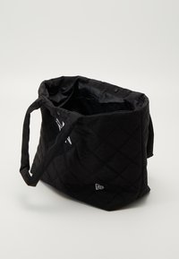 Saco tote preto acolchoado com duas alças, apresentando um fecho de botão e um detalhe com o logótipo. Textura suave, interior espaçoso.