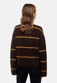 Pull en tricot marron avec des rayures horizontales jaunes, coupe ample, manches larges et texture côtelée. Coupé à la taille, avec un ourlet arrondi.