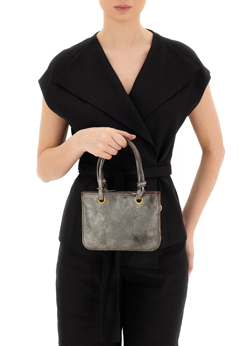 Piccola borsa a tracolla in pelle metallicamente argentata con finitura testurizzata, doppi manici e hardware dorato. Indossata da un modello in una maglietta nera.