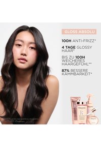 Produkty Kerastase Gloss Absolu w różowym i złotym opakowaniu. Opis produktów podkreśla efekty przeciw puszeniu i uzyskiwania połysku.