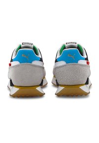 Paire de baskets Puma vue de dos, avec des panneaux bleus au talon, du daim gris, des semelles intermédiaires blanches et des semelles extérieures couleur gomme.