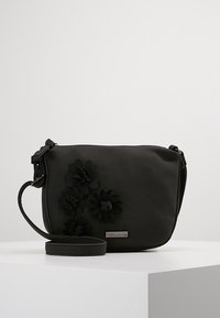 Schwarze synthetische Umhängetasche mit floralen Akzenten, flaches Design, verstellbarer Tragegurt und silberne Hardware-Logodetails. Glatte Oberfläche.