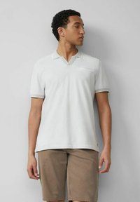 Hellgraues Poloshirt mit V-Ausschnitt, kurzen Ärmeln und einer Brusttasche. Dünne kontrastierende Borte am Kragen und an den Ärmeln.