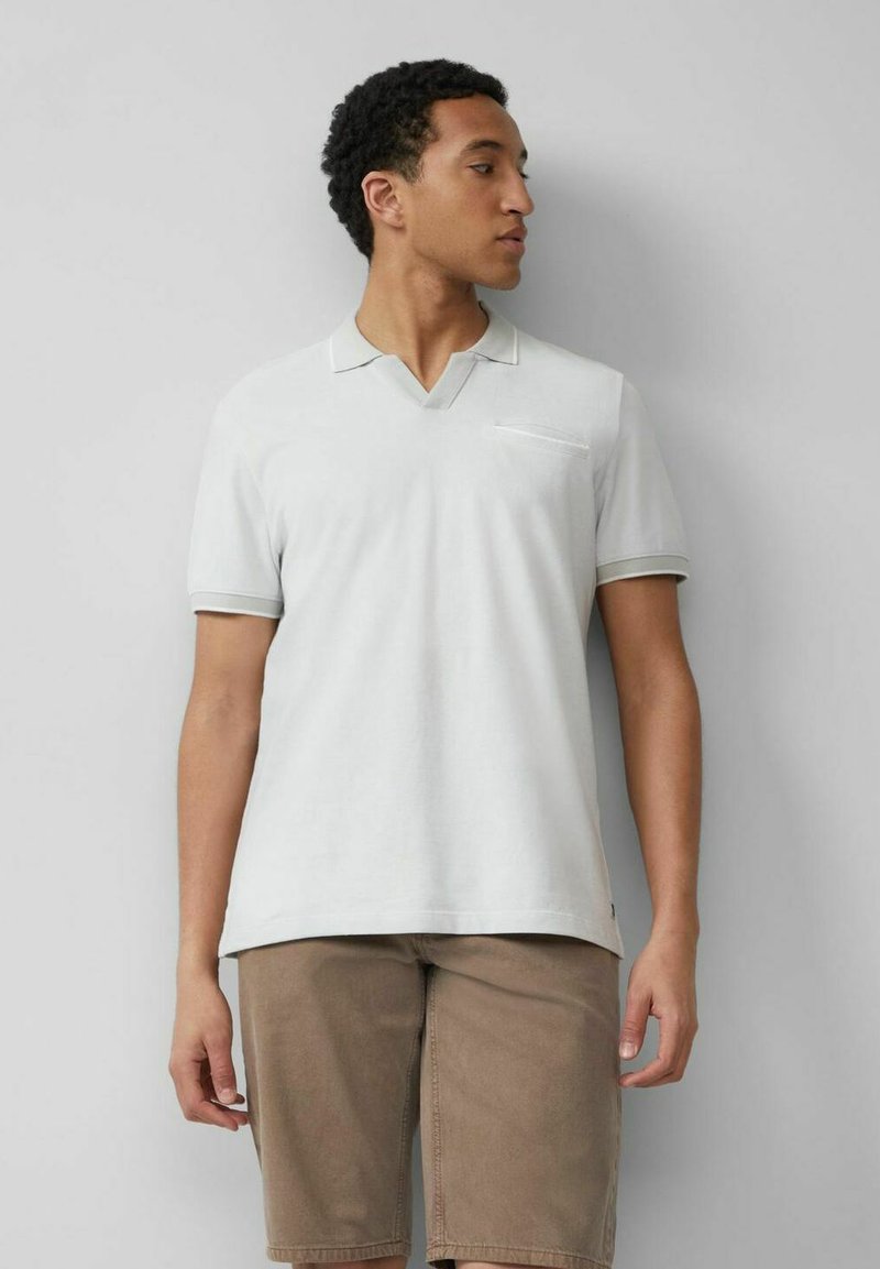 Hellgraues Poloshirt mit V-Ausschnitt, kurzen Ärmeln und einer Brusttasche. Dünne kontrastierende Borte am Kragen und an den Ärmeln.