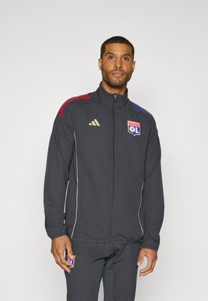 Adidas zip-up jakke i mørkegrå, med røde og blå skulderstriper, gullfargede detaljer og et logo-patch. Lettvektig, atletisk design.
