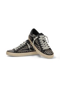 Zapatillas de cuero negro con tachuelas plateadas, cordones grises y una suela de goma marrón. Presentan un patrón de zigzag en el lateral.