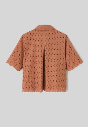 Blouse rose poudré à manches courtes avec bords festonnés et motif floral ajouré, vue de dos.