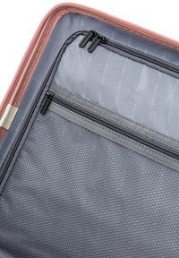 Innenansicht einer pink- und grau-gestreiften Reisetasche mit Reißverschluss, die ein Hauptfach und eine Netztasche mit strukturiertem Stoff und subtiler Markenkennzeichnung bietet.