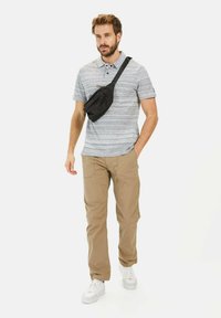 Grå og hvid stribet polo-shirt, beige bukser, sort sling bag og hvide sneakers. Sættet har en afslappet pasform og en uformel stil.