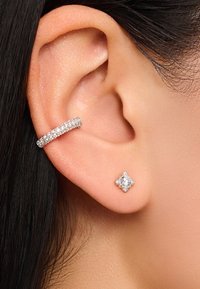 Silberne Creolen mit einer Reihe kleiner funkelnder Steine, kombiniert mit einem quadratischen Ohrstecker, der einen zentralen Edelstein mit umlaufenden Akzenten zeigt.