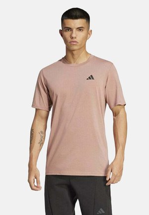 Camiseta deportiva de manga corta, color rosa claro, con cuello redondo y logo negro de Adidas en el lado izquierdo del pecho, fabricada con tejido transpirable.
