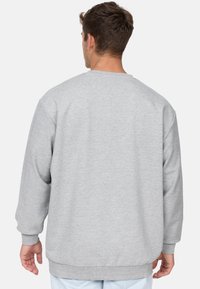 Szara bluza z okrągłym dekoltem i długimi rękawami. Posiada ściągacze na mankietach i na dole, wykonana z miękkiego, teksturalnego materiału. Prosty design.