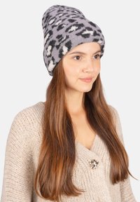 Grau gestrickte Mütze mit einem schwarz-weißen abstrakten Muster, aus weichem Stoff gefertigt. Sie hat ein lässiges Design und eine flexible Passform.