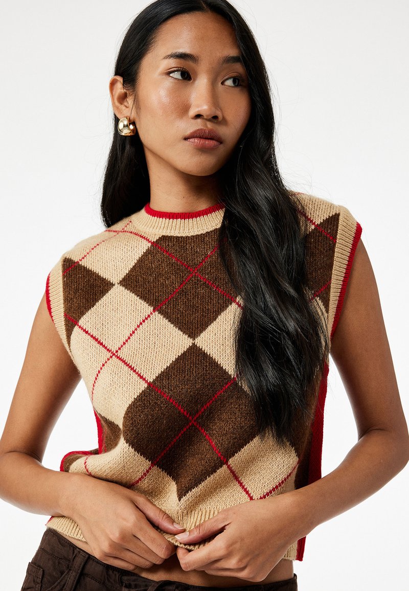Ärmelloser Strickpullover mit einem beigen und braunen Argyle-Muster sowie roten Akzenten. Gerippter Rundhalsausschnitt und strukturierter Stoff.