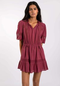 Vestido burdeos con escote en V, mangas cortas abullonadas, detalles de encaje y cintura elástica. Presenta un dobladillo de volantes en capas y tejido texturizado.
