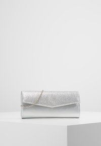 Bolso de mano plateado con una solapa frontal brillante, cuerpo metálico liso y una correa de cadena. Presenta una forma rectangular y un diseño angular.