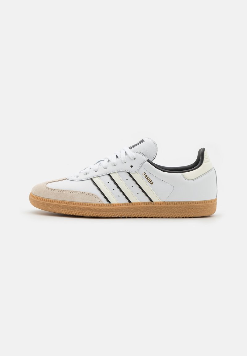 White leather sneakers with black stripes, gum rubber outsole, and beige suede toe cap. Features soft lining and textured back heel.