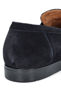 Granatowe zamszowe buty z okrągłym tyłem, kontrastowym przeszyciem i teksturowaną czarną gumową podeszwą. Wnętrze ma beżowe wykończenie.