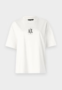 T-shirt blanc à manches courtes avec le logo noir Armani Exchange centré sur la poitrine sur un fond gris clair.