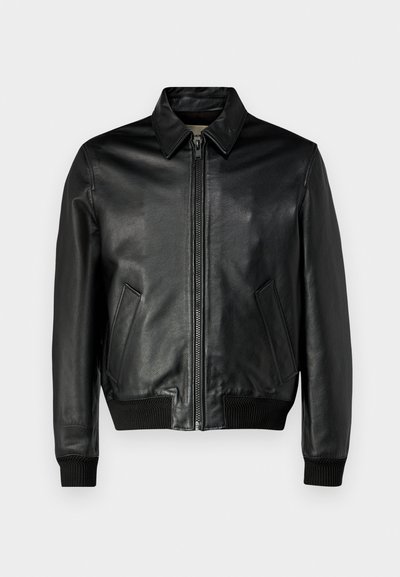 Black leather jacket with a zip front, pointed collar, and two side pockets. Ribbed cuffs and hem enhance the fitted design. Soft texture.