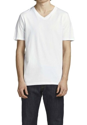 Witte v-hals t-shirt van katoen, korte mouwen, ontspannen pasvorm, effen textuur, gecombineerd met donkerblauwe spijkerbroek.