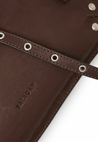 Portafoglio in pelle marrone con finitura testurizzata, dotato di occhielli in argento e una cintura cucita. Logo "Balagan" impresso visibile.