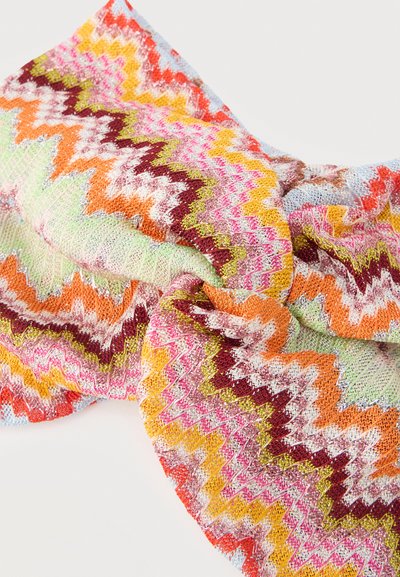 Pletená látka skrútená v strede so zygzakovitými vzormi v ružovej, oranžovej, žltej, bordovej, zelenej, bielej a svetlomodrej farbe.