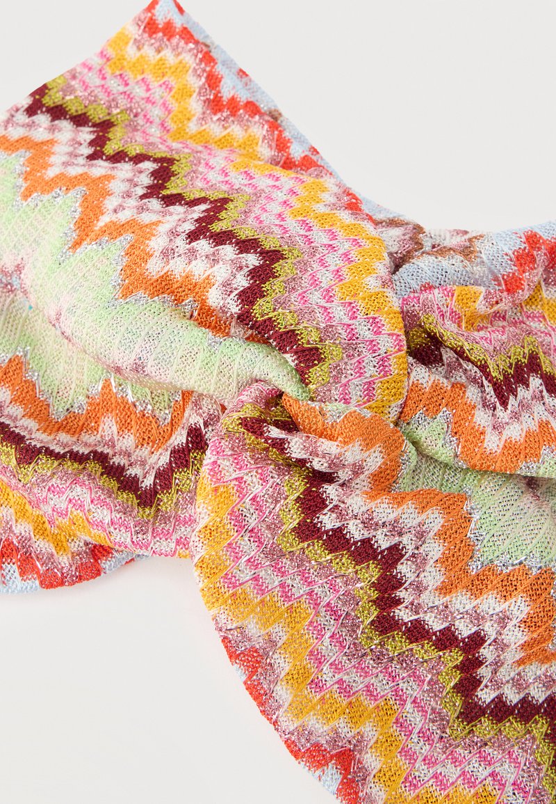 Gebreide stof gedraaid in het midden met zigzagpatronen in roze, oranje, geel, bordeaux, groen, wit en lichtblauwe kleuren.