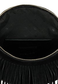 Interno di una borsa in suede nero con chiusura a zip, hardware dorato e fodera in tessuto nero testurizzato caratterizzata da un sottile motivo a diamante.