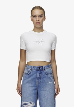White cropped t-shirt with short sleeves and embossed lettering "PECADOR" on the front, paired with light blue distressed high-waisted jeans.