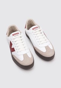 Sneaker bianche con accentuazioni rosse e beige. Parte superiore in morbida pelle con punta in suede, lacci piatti e suola in gomma. Branding sulla linguetta.