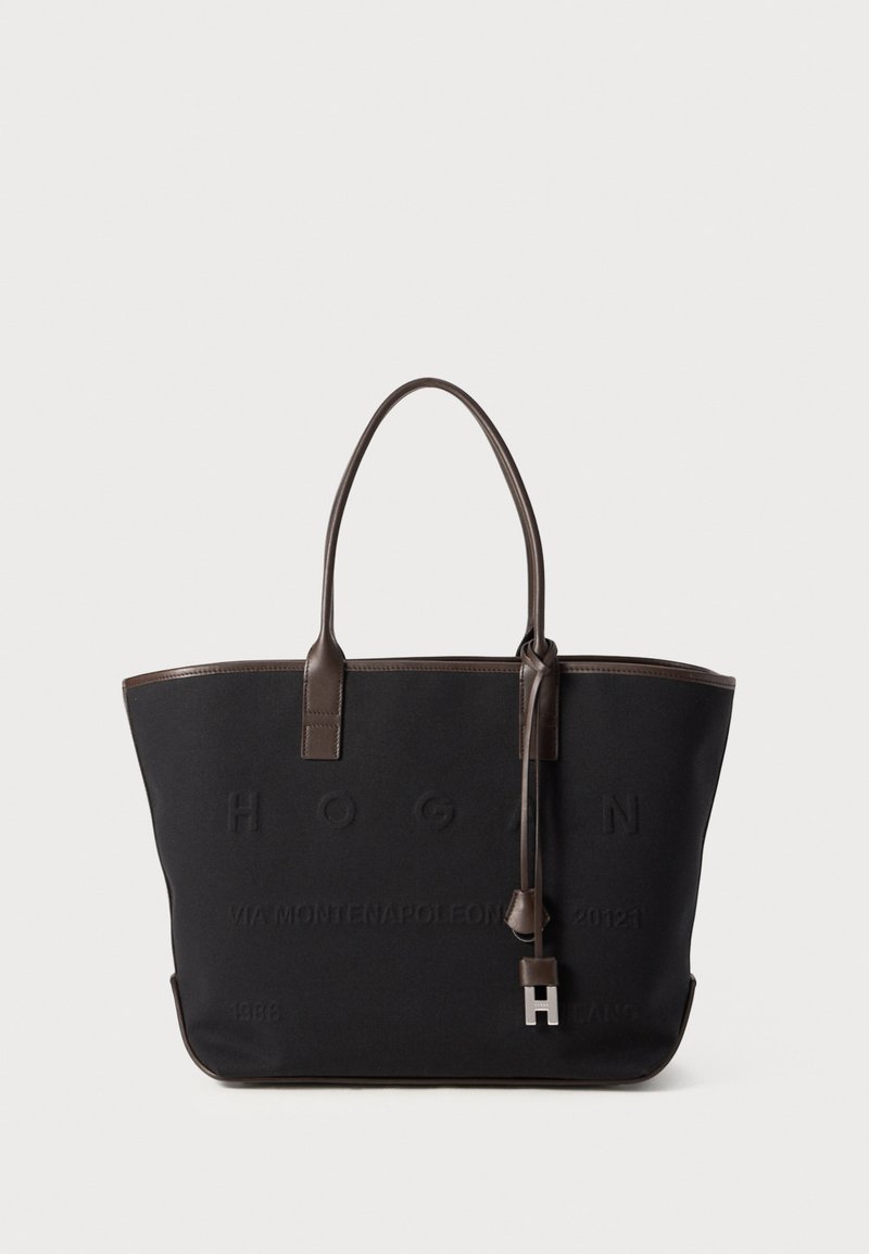 Sac fourre-tout en toile noire avec des poignées en cuir marron, des détails du logo en relief, un charme détachable et une forme structurée.