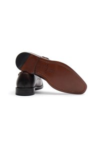 Hnědé kožené společenské boty s elegantním designem, kulatou špičkou a světlou koženou podrážkou. Významné švy a decentní logo na podrážce.