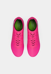 Zapatillas deportivas de color rosa brillante con plantillas verdes, detalles y cordones negros, vistas desde arriba sobre un fondo blanco.
