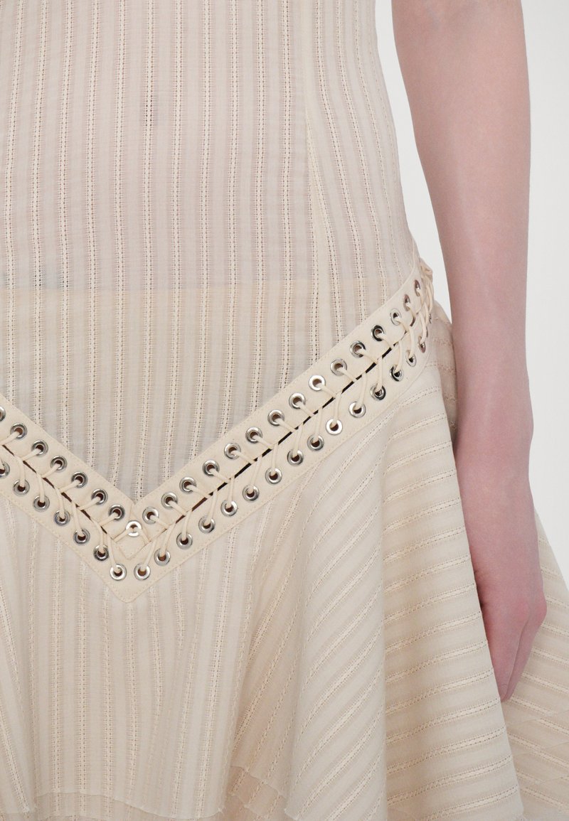 Beige dress with vertical stripes, features a V-shaped neckline, and a decorative grommet and lace-up detail at the waist.