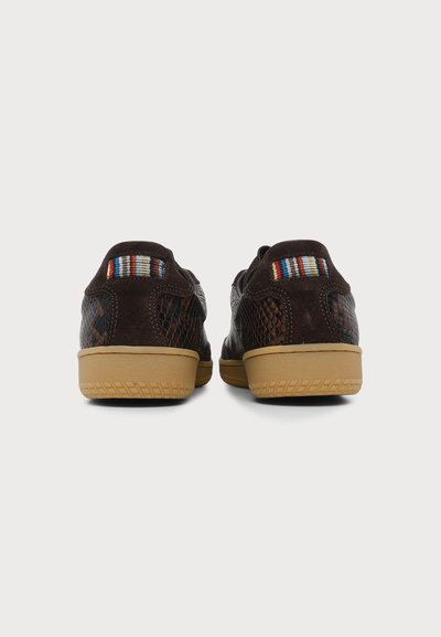 Paire de baskets marron foncé avec côtés texturés, semelles en caoutchouc couleur fauve et détail en tissu rayé multicolore à l'arrière, vue de dos.